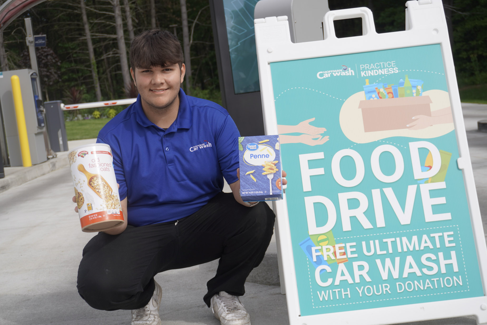 A Hoffman Car Wash Team Member in front of a Food Drive sign with donations in his hand