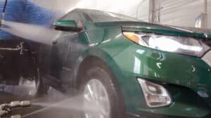 Green car going through the car wash tunnel